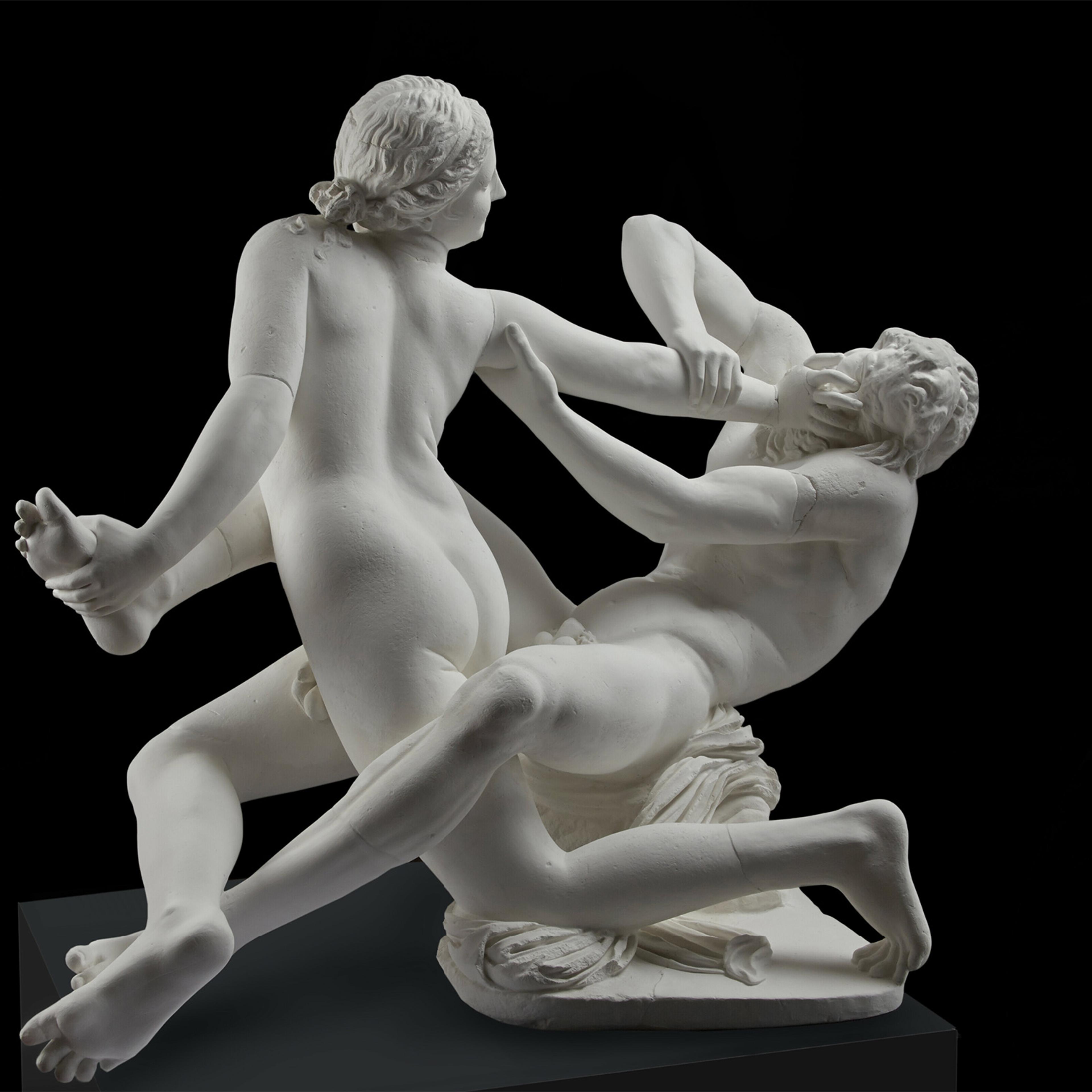 Marble sculpture of a dynamic struggle between two naked figures on a dark background, showcasing intricate details and movement.