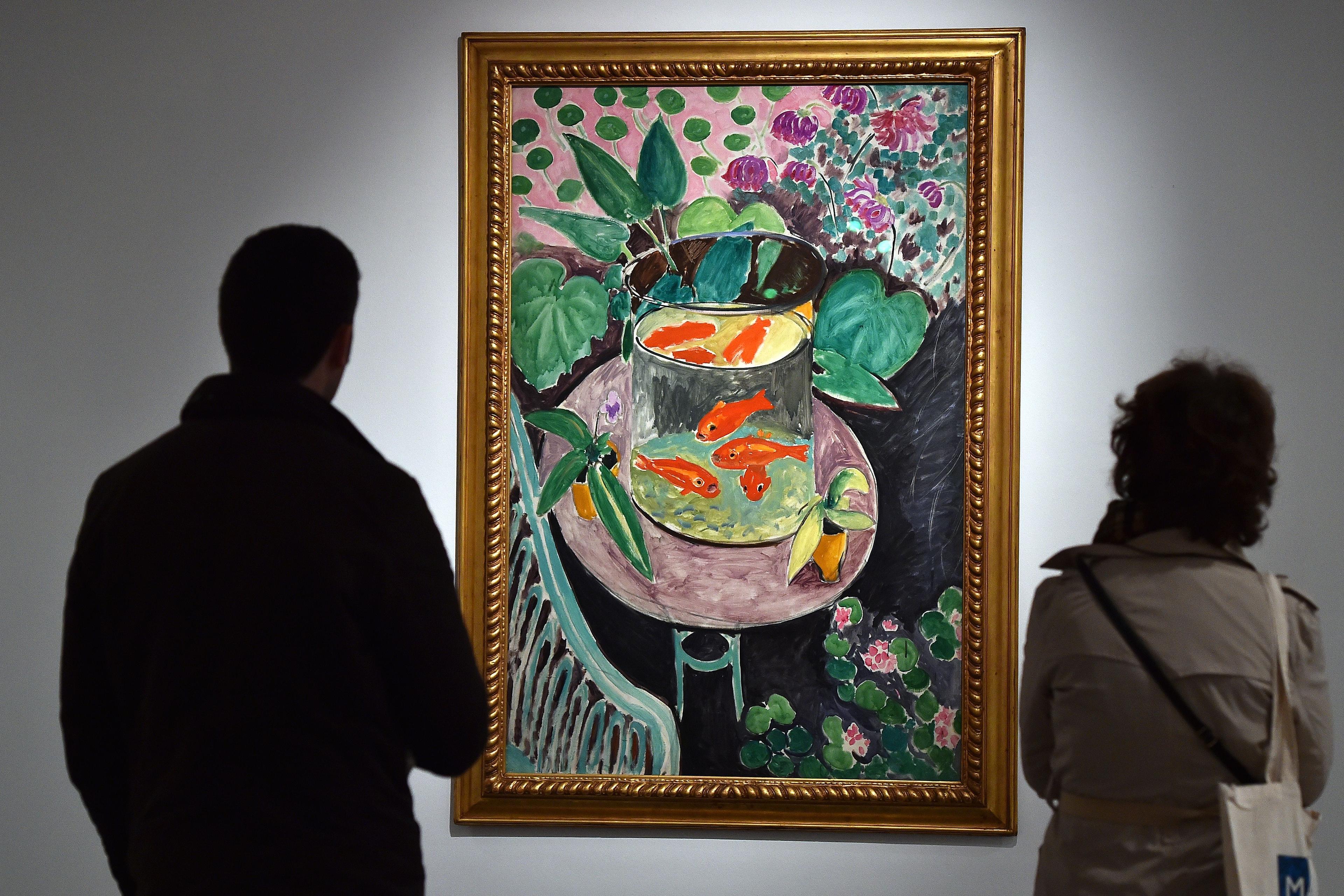 Painting of goldfish in a bowl surrounded by plants with two people viewing in a gallery setting.
