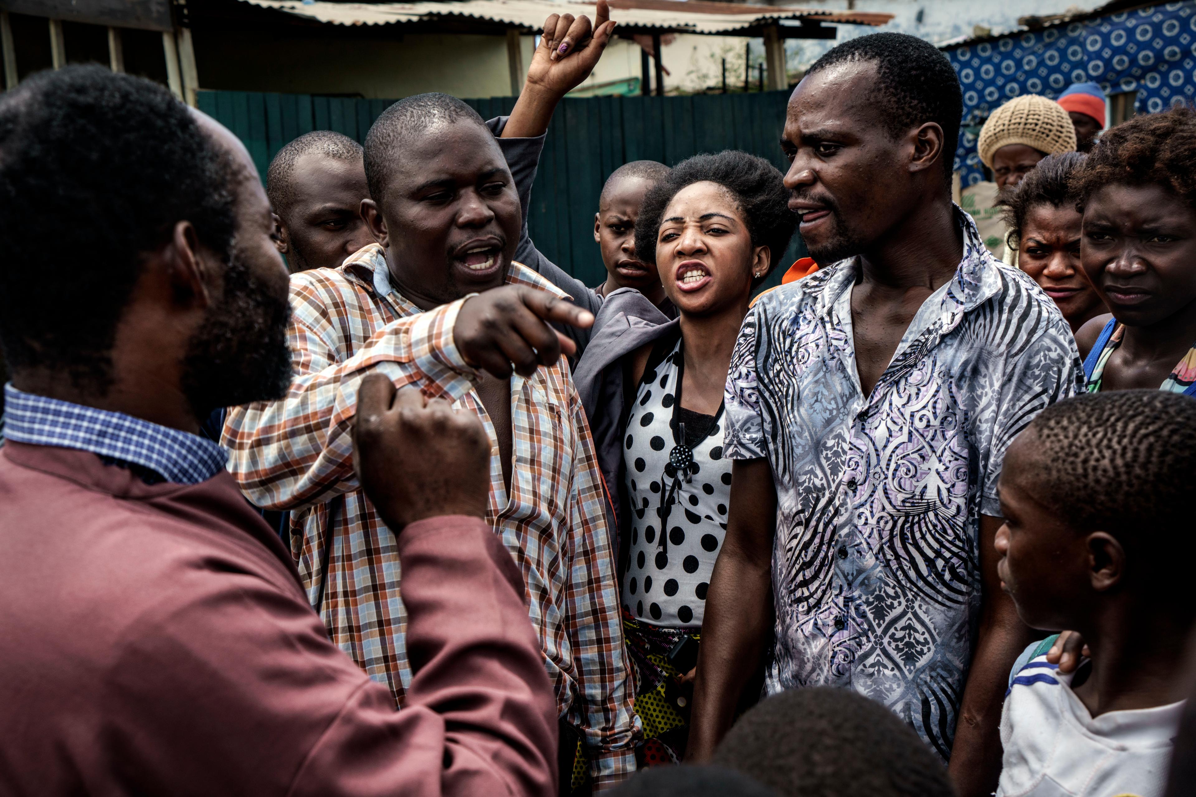 A group of people engaged in a heated discussion outdoors with diverse expressions and gestures.